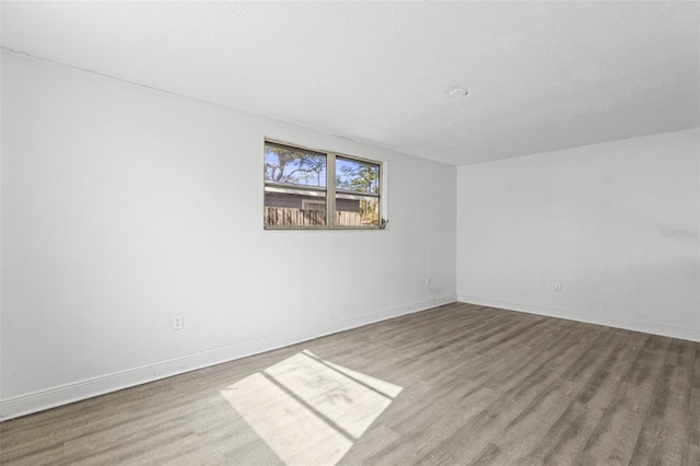unfurnished room featuring baseboards, a textured ceiling, and wood finished floors