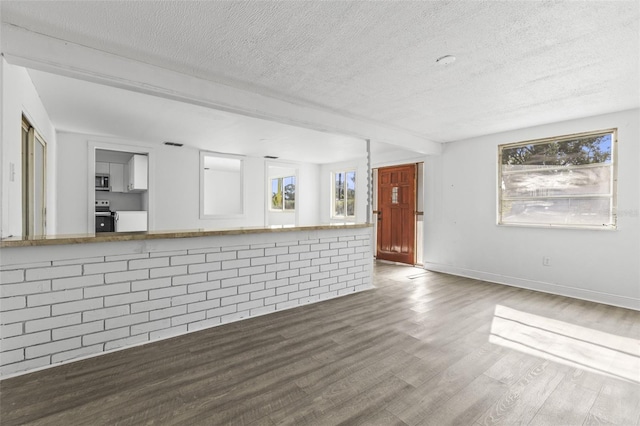 unfurnished living room with wood finished floors, baseboards, and a textured ceiling