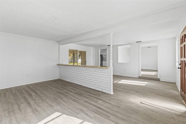 unfurnished living room with visible vents, wood finished floors, and baseboards