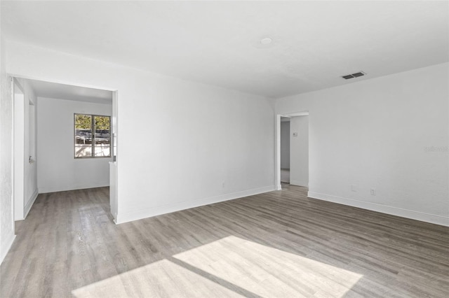 spare room featuring visible vents, baseboards, and wood finished floors
