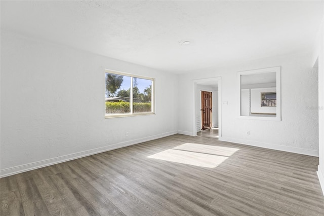 spare room with baseboards and wood finished floors