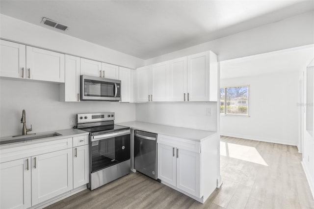 kitchen with visible vents, a sink, white cabinetry, stainless steel appliances, and light countertops