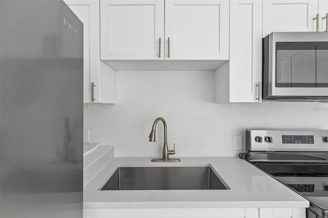 kitchen with white cabinets, appliances with stainless steel finishes, light countertops, and a sink