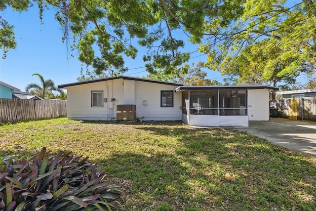 ranch-style house featuring a front yard, fence, and a sunroom