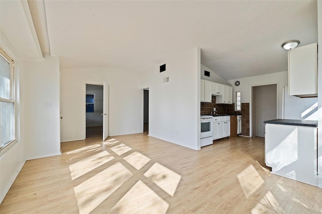 kitchen with lofted ceiling, electric range, tasteful backsplash, light hardwood / wood-style floors, and white cabinetry