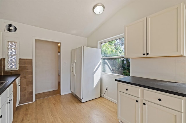 kitchen with white refrigerator with ice dispenser, light hardwood / wood-style floors, and white cabinetry