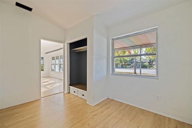 unfurnished bedroom featuring vaulted ceiling, light wood-type flooring, and a closet