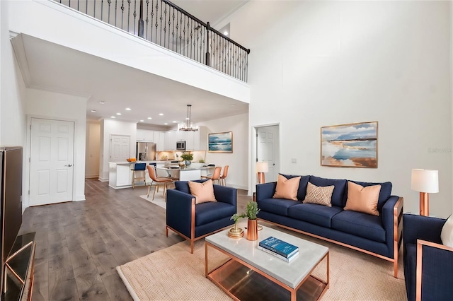 living room with a high ceiling, a notable chandelier, and wood-type flooring