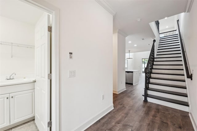 corridor with sink, ornamental molding, and dark wood-type flooring