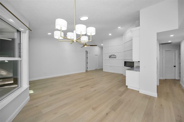 unfurnished living room featuring a notable chandelier, built in features, a textured ceiling, and light hardwood / wood-style flooring