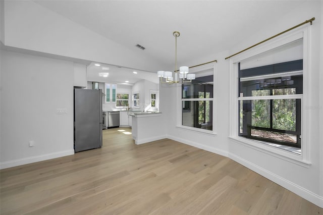 unfurnished dining area featuring an inviting chandelier, light wood-type flooring, and vaulted ceiling