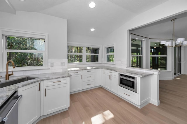 kitchen with white cabinetry, dishwasher, light stone countertops, sink, and lofted ceiling