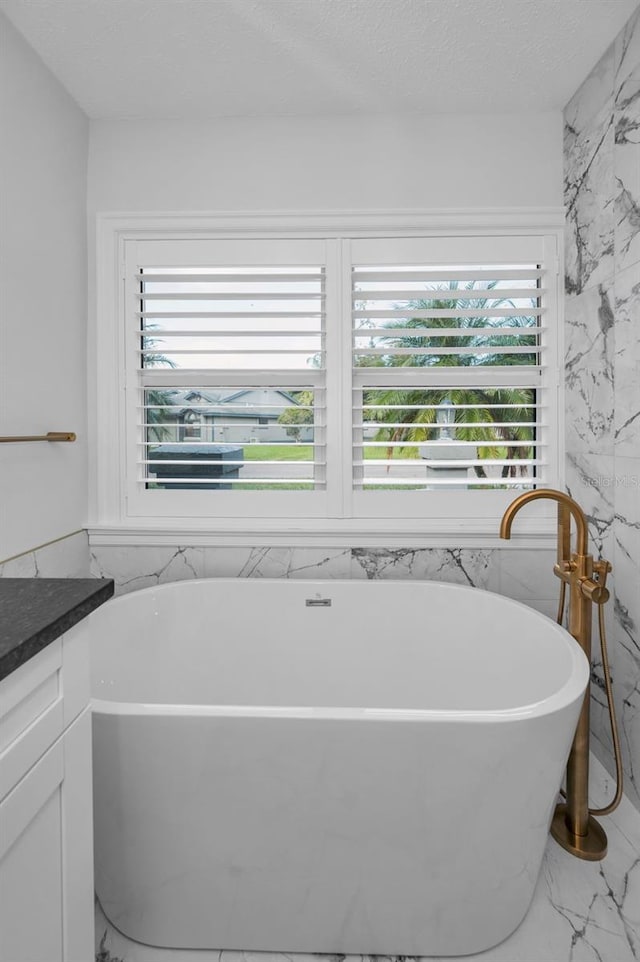 bathroom featuring a bathtub, a textured ceiling, vanity, and tile walls