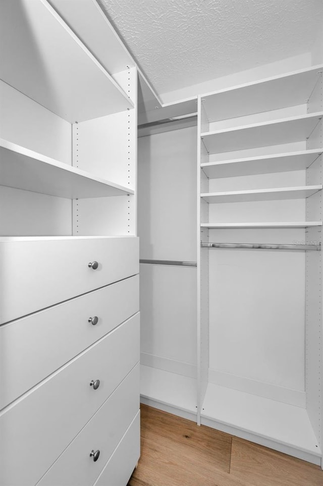 walk in closet with light hardwood / wood-style floors