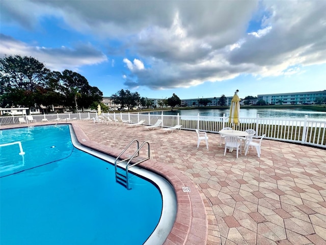 view of swimming pool featuring a patio and a water view