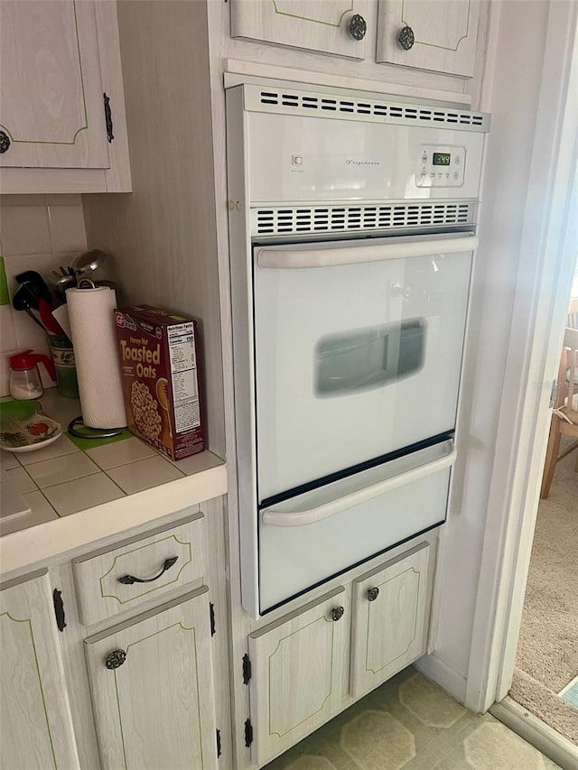 interior details featuring tile countertops, backsplash, and oven