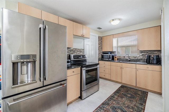 kitchen with light brown cabinetry, backsplash, stainless steel appliances, and sink