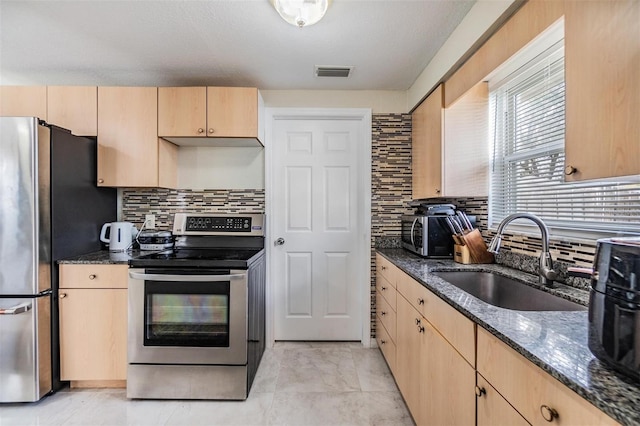 kitchen featuring backsplash, dark stone countertops, sink, and appliances with stainless steel finishes