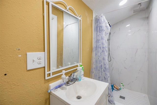 bathroom with a textured ceiling, vanity, and curtained shower