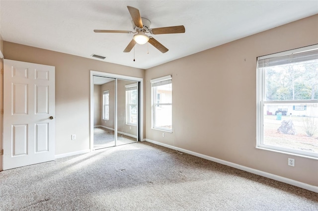 unfurnished bedroom featuring carpet floors, a closet, multiple windows, and ceiling fan