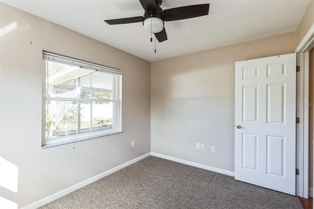 empty room featuring dark colored carpet and ceiling fan