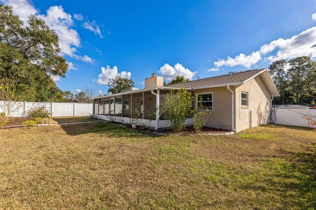 back of house with a sunroom and a yard