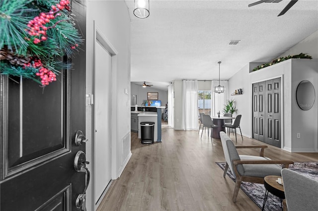 entrance foyer with hardwood / wood-style floors, ceiling fan with notable chandelier, lofted ceiling, and a textured ceiling