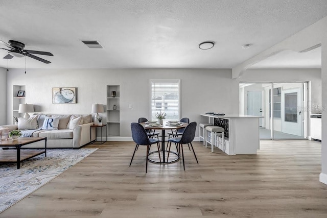 dining space with ceiling fan, a textured ceiling, and light hardwood / wood-style flooring