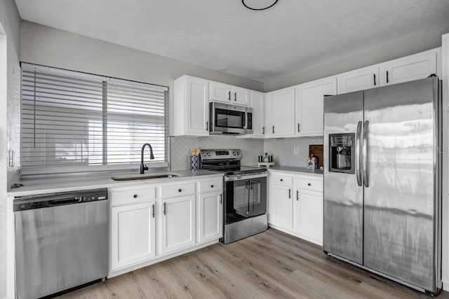 kitchen featuring white cabinetry, sink, stainless steel appliances, tasteful backsplash, and light hardwood / wood-style floors