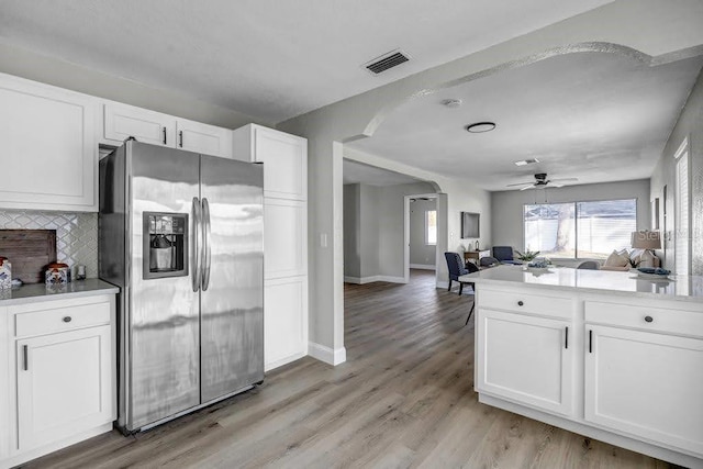 kitchen with white cabinets, decorative backsplash, ceiling fan, light hardwood / wood-style floors, and stainless steel fridge with ice dispenser