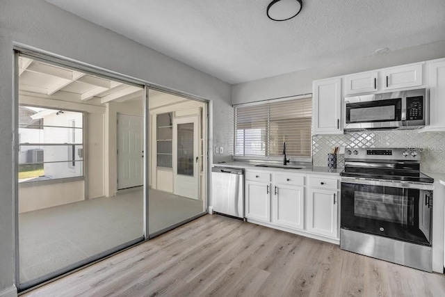 kitchen with white cabinets, stainless steel appliances, and a wealth of natural light