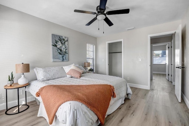 bedroom with multiple windows, ceiling fan, a closet, and light wood-type flooring