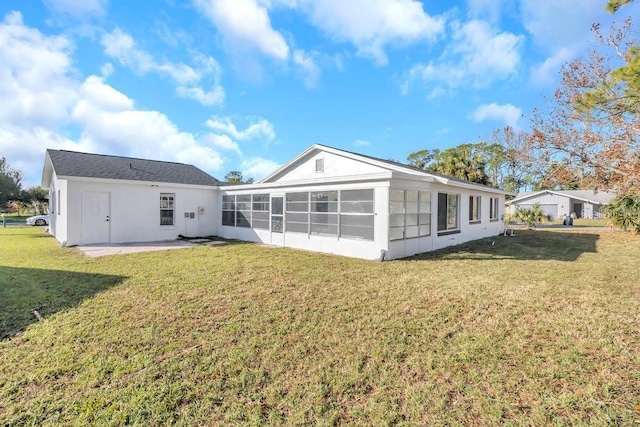 rear view of house with a patio, a lawn, and a sunroom