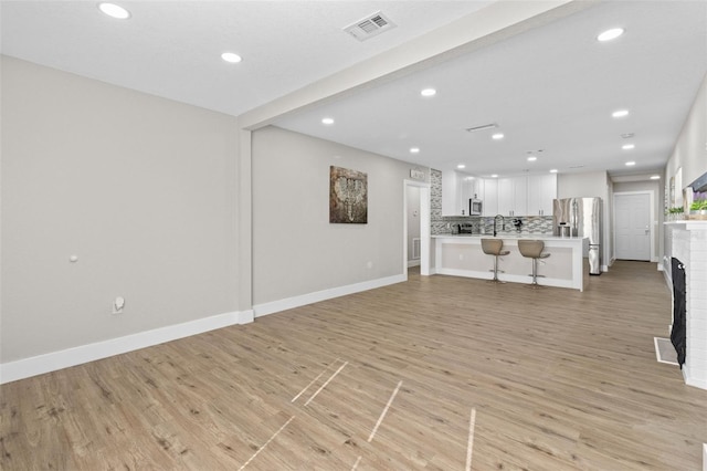 unfurnished living room with a fireplace, light wood-type flooring, and sink