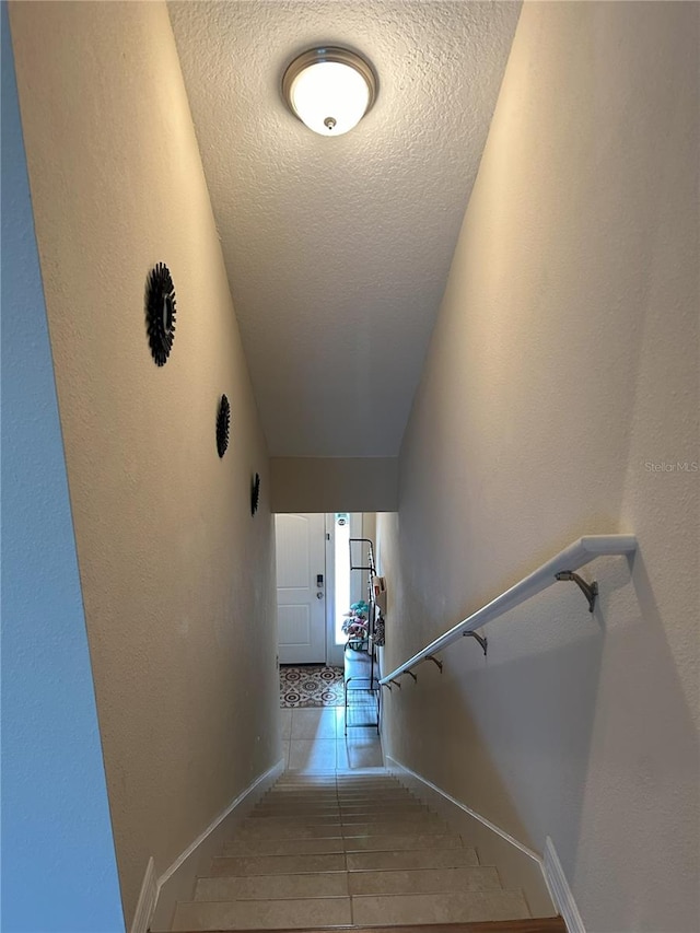 staircase featuring a textured ceiling and tile patterned floors