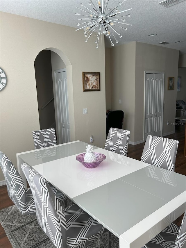 dining space with a chandelier, dark wood-type flooring, and a textured ceiling