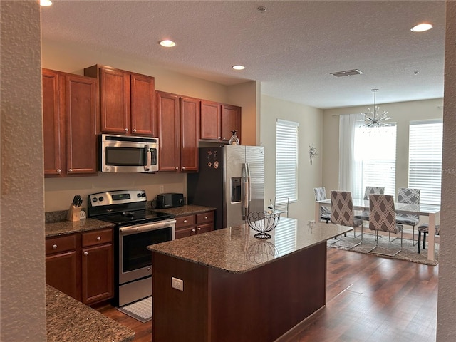 kitchen featuring an inviting chandelier, appliances with stainless steel finishes, hanging light fixtures, and a kitchen island