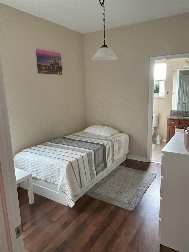 bedroom with ensuite bathroom and dark hardwood / wood-style flooring