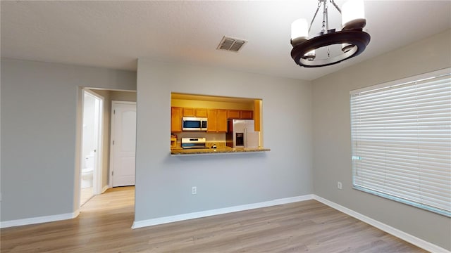 unfurnished living room with light hardwood / wood-style floors and a chandelier