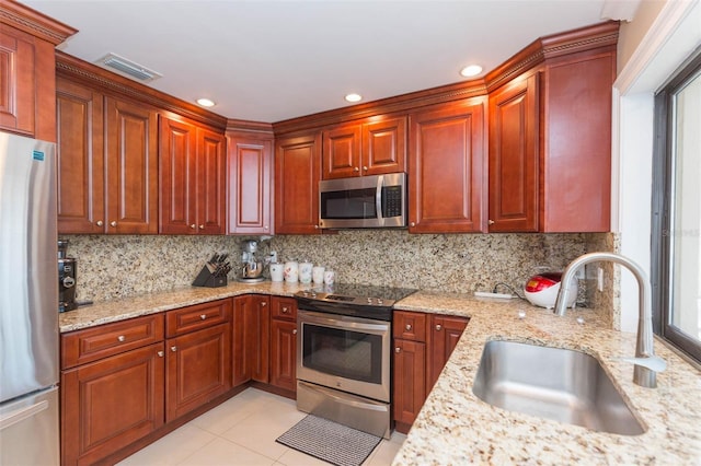 kitchen featuring sink, light tile patterned floors, appliances with stainless steel finishes, tasteful backsplash, and light stone counters