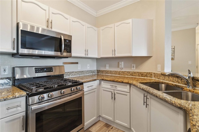 kitchen with white cabinets, light stone counters, sink, and appliances with stainless steel finishes