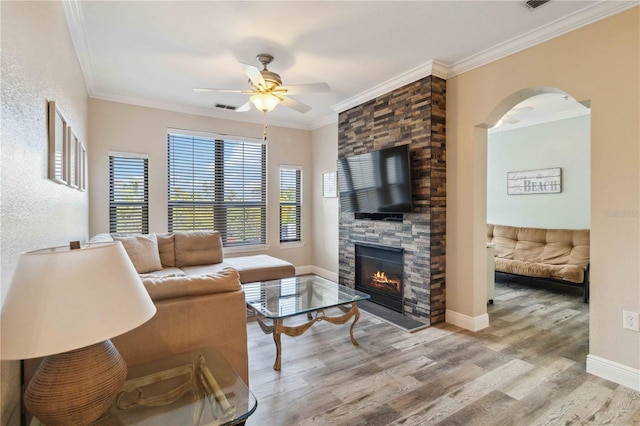 living room with ceiling fan, a fireplace, wood-type flooring, and ornamental molding