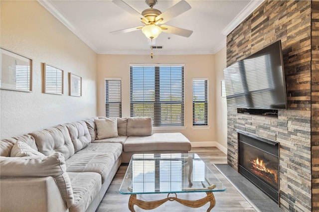 living room featuring a stone fireplace, crown molding, light hardwood / wood-style flooring, and a healthy amount of sunlight