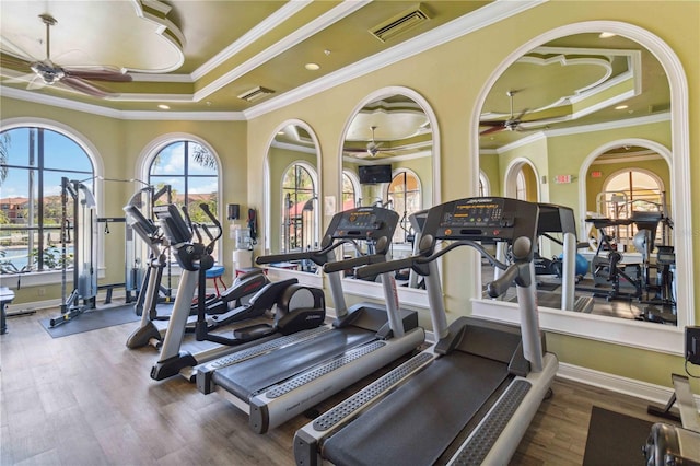 gym with hardwood / wood-style floors, ornamental molding, and a tray ceiling