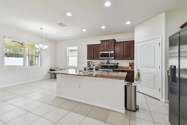 kitchen featuring a chandelier, stainless steel appliances, a wealth of natural light, and an island with sink