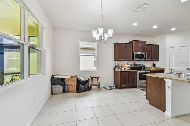 kitchen featuring light stone countertops, sink, stainless steel appliances, a notable chandelier, and decorative light fixtures