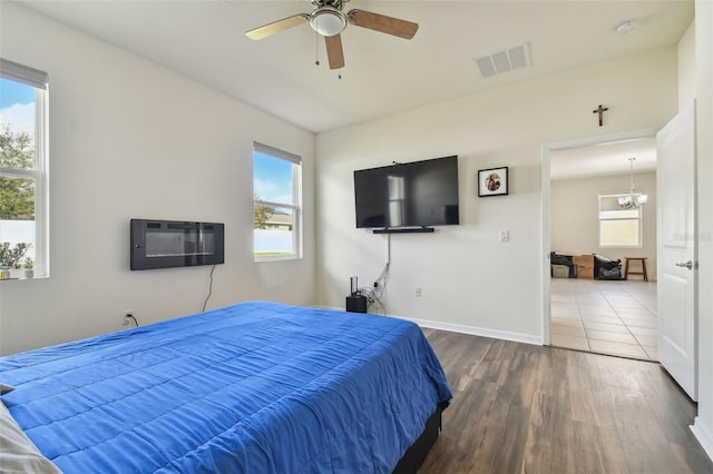 bedroom with a wall unit AC, dark hardwood / wood-style flooring, and ceiling fan with notable chandelier