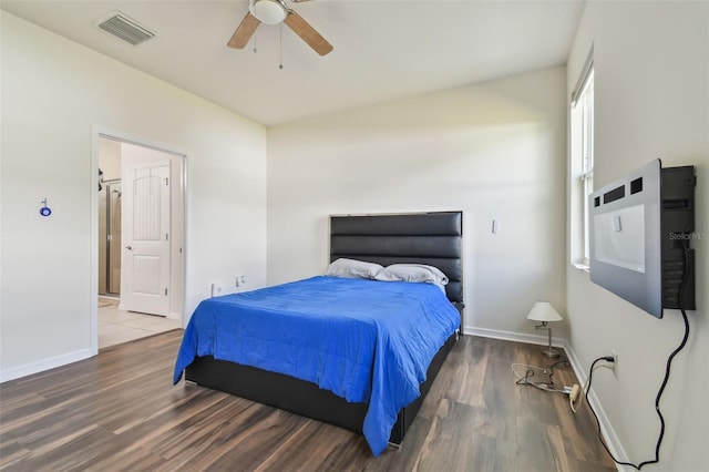 bedroom featuring dark hardwood / wood-style flooring, ceiling fan, and connected bathroom