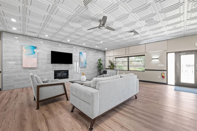 living room with ceiling fan, a fireplace, and light hardwood / wood-style flooring