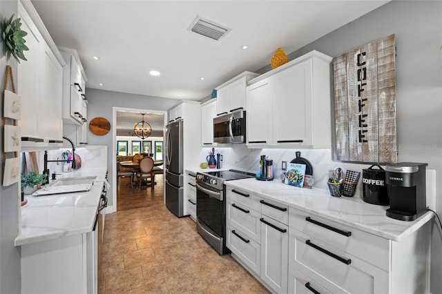 kitchen featuring a notable chandelier, light stone counters, white cabinetry, and stainless steel appliances